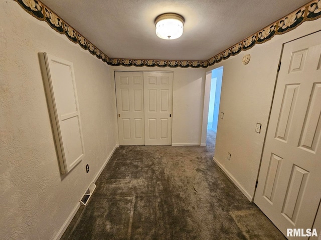 unfurnished bedroom featuring a closet, baseboards, visible vents, and dark colored carpet