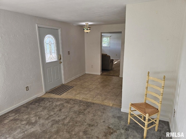 carpeted entrance foyer featuring baseboards and a textured wall