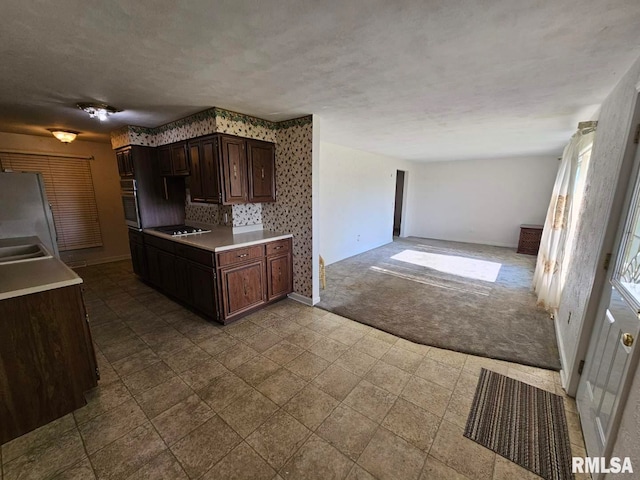 kitchen featuring dark carpet, open floor plan, baseboards, and light countertops