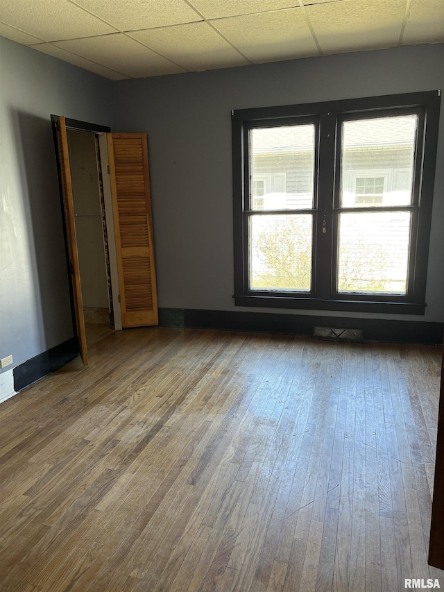 920 S 12th St, Herrin, IL 62948 - unfurnished bedroom featuring wood-type flooring, baseboards, a drop ceiling, and multiple windows