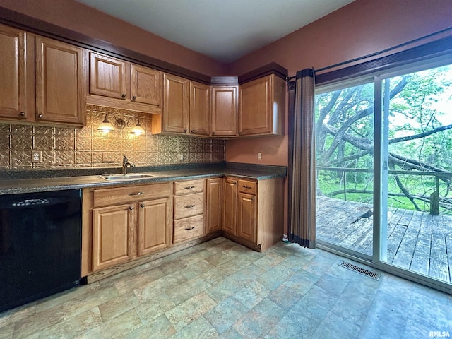 kitchen with visible vents, dark countertops, black dishwasher, stone finish floor, and a sink