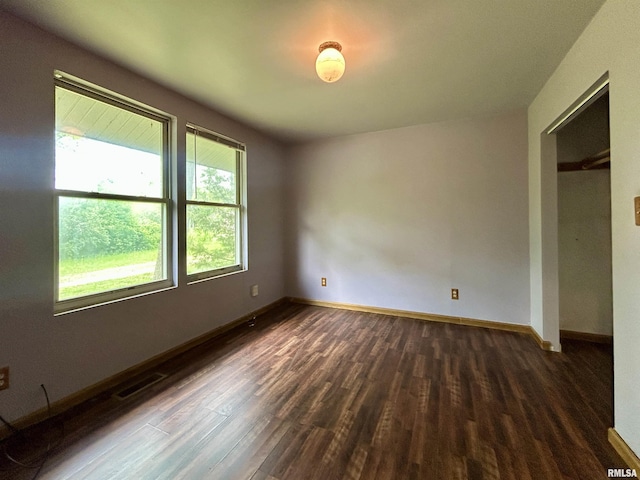 unfurnished room featuring baseboards, visible vents, and dark wood-type flooring