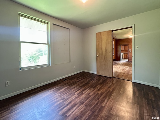 unfurnished bedroom with dark wood-type flooring, baseboards, and multiple windows