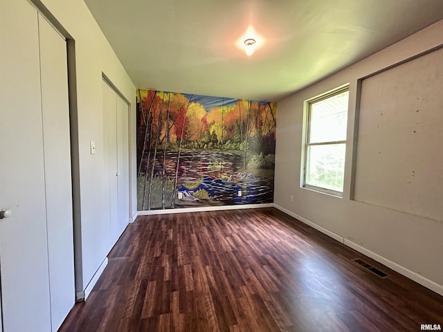 unfurnished bedroom featuring visible vents, baseboards, and wood finished floors