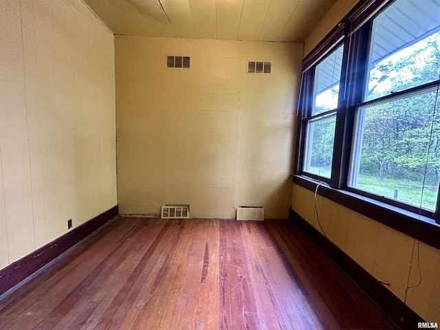 empty room with wood-type flooring and visible vents