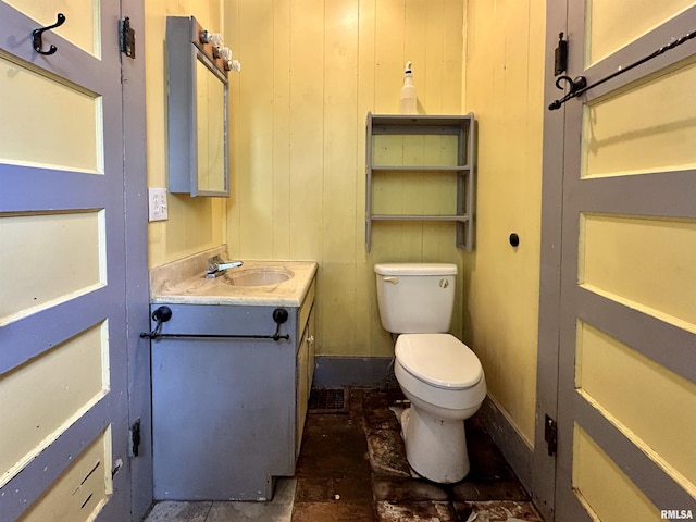 bathroom featuring vanity, stone finish flooring, baseboards, and toilet
