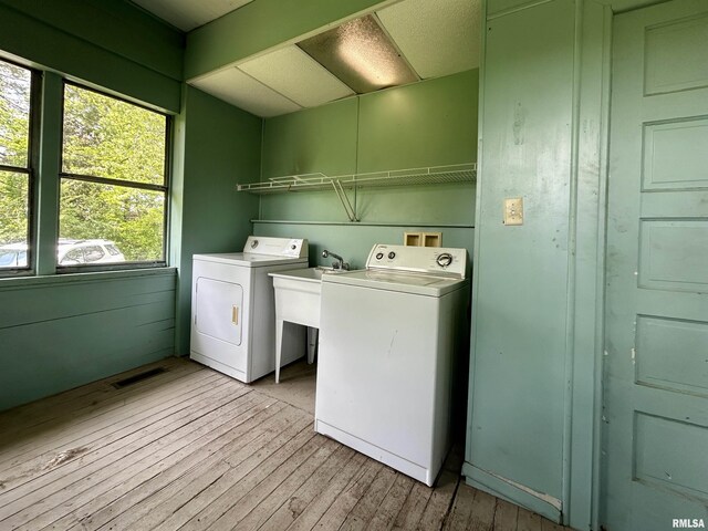 laundry area featuring laundry area, visible vents, washing machine and dryer, a sink, and light wood finished floors