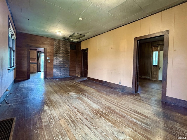 unfurnished living room featuring wooden walls, visible vents, and hardwood / wood-style floors
