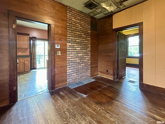 empty room featuring wood walls, hardwood / wood-style flooring, and visible vents