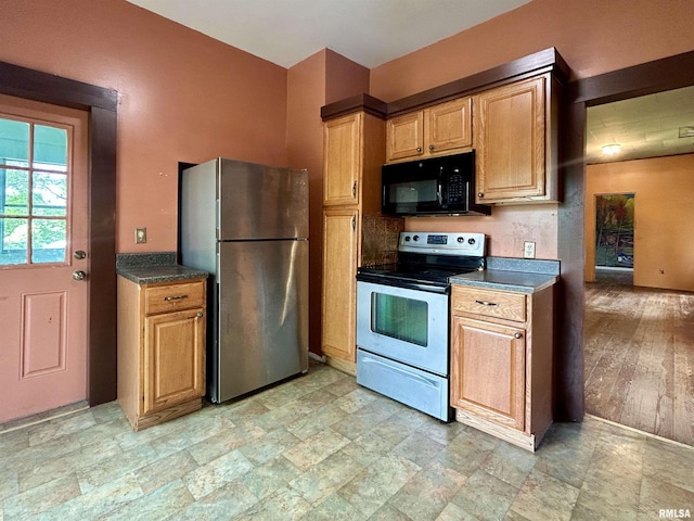 kitchen with appliances with stainless steel finishes, stone finish floor, and dark countertops