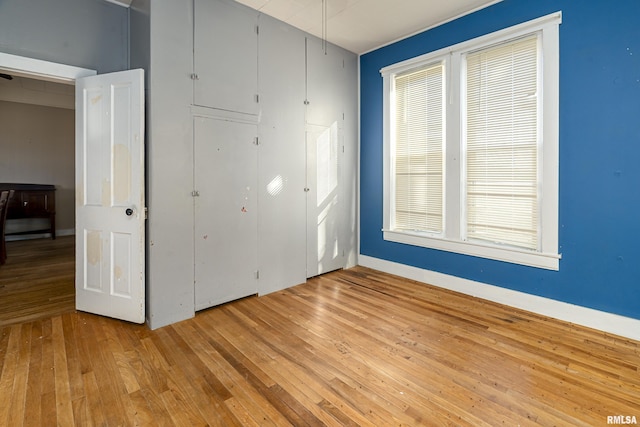 spare room featuring light wood-style floors, baseboards, and a wealth of natural light