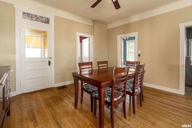 dining room featuring baseboards, ceiling fan, wood finished floors, and a wealth of natural light