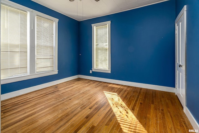 empty room with wood-type flooring, a ceiling fan, and baseboards