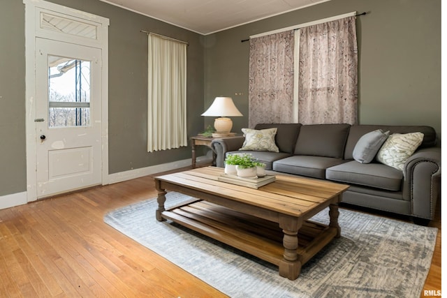 living area with baseboards, crown molding, and hardwood / wood-style flooring