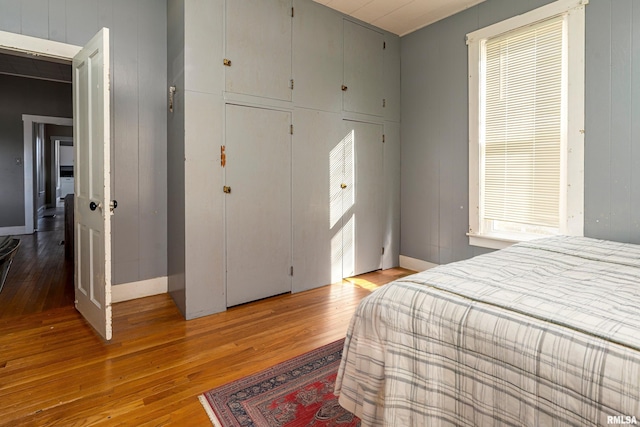 bedroom with a closet, light wood-style flooring, and baseboards