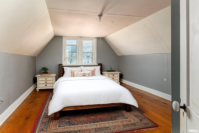 bedroom with baseboards, wood finished floors, and lofted ceiling