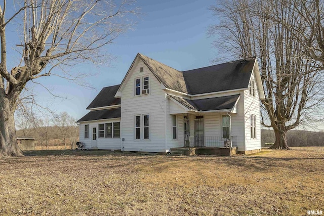 view of front facade featuring roof with shingles, covered porch, and a front lawn