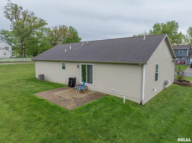 back of property with roof with shingles, a patio, a lawn, and central AC