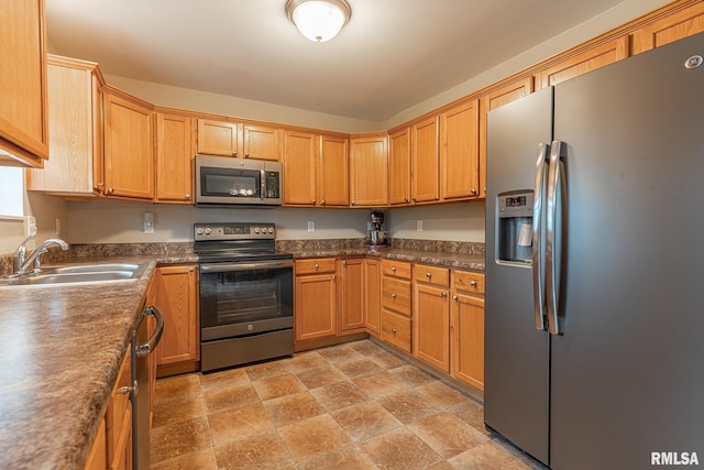 kitchen with a sink, appliances with stainless steel finishes, and stone finish floor