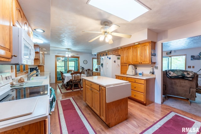 kitchen with white appliances, ceiling fan, light wood-type flooring, light countertops, and a sink