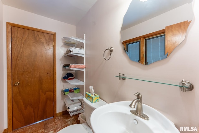 half bathroom featuring toilet, a sink, and marble finish floor