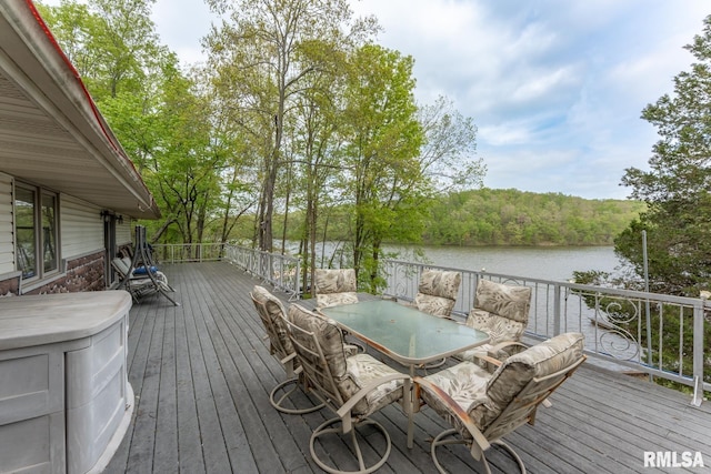 deck with outdoor dining area and a water view