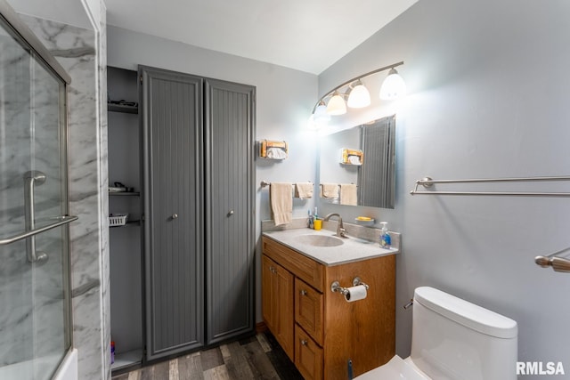 full bath featuring toilet, a shower with door, wood finished floors, and vanity