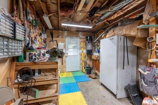 below grade area with freestanding refrigerator and a workshop area