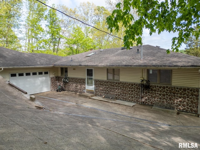 view of front facade with an attached garage, a shingled roof, and driveway