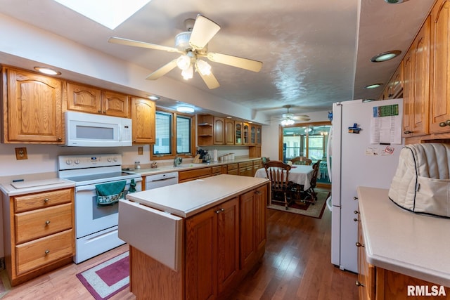 kitchen with a sink, white appliances, a center island, a ceiling fan, and light wood finished floors