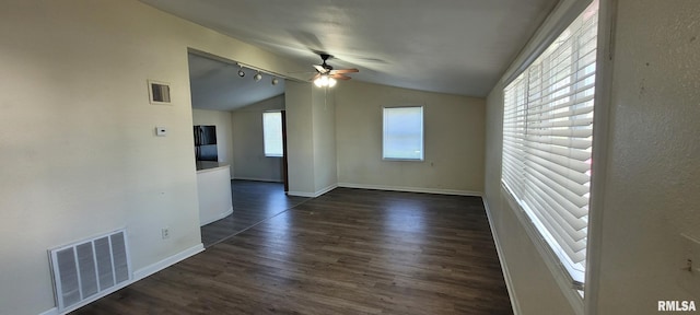 spare room featuring ceiling fan, visible vents, baseboards, dark wood-style floors, and lofted ceiling