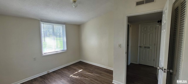 empty room with baseboards, dark wood-style floors, a textured ceiling, and visible vents
