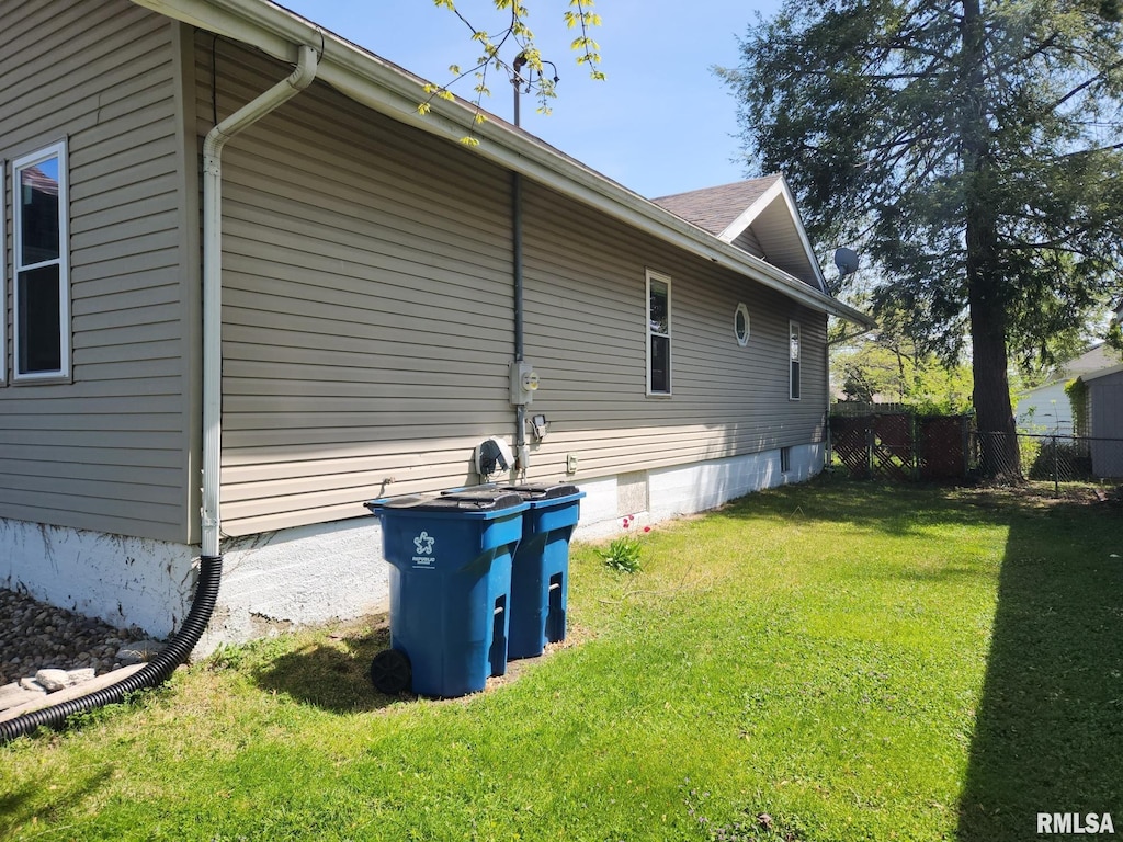 view of home's exterior with fence and a lawn