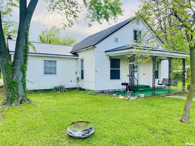view of front of property with metal roof, a porch, and a front lawn