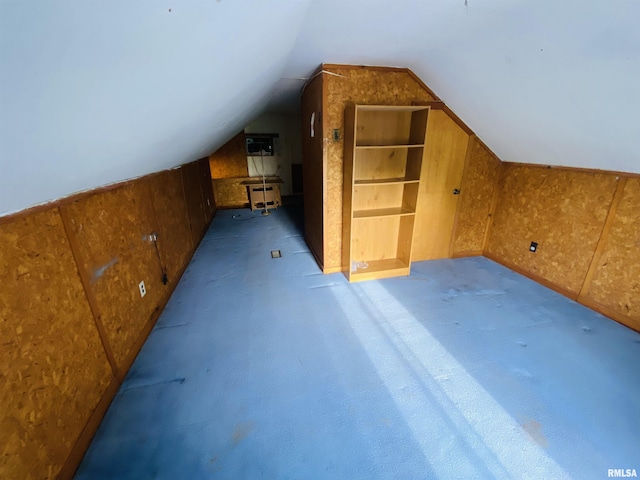 bonus room with wooden walls, carpet, and lofted ceiling