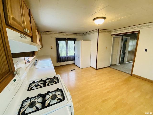 kitchen featuring brown cabinetry, white appliances, baseboards, under cabinet range hood, and a sink