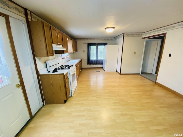 kitchen with brown cabinetry, white appliances, light wood-type flooring, light countertops, and under cabinet range hood