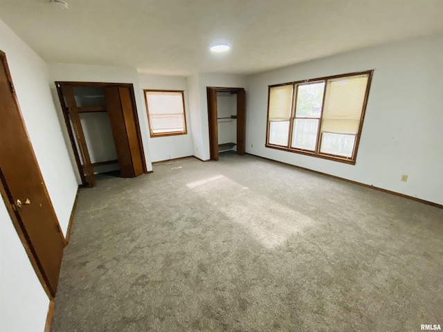 unfurnished bedroom with baseboards, multiple windows, and carpet flooring