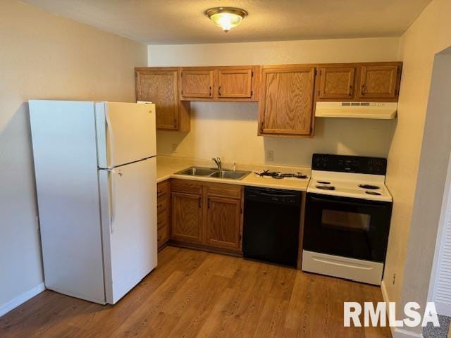 kitchen featuring freestanding refrigerator, black dishwasher, under cabinet range hood, a sink, and range with electric cooktop