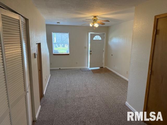 carpeted foyer featuring baseboards and ceiling fan