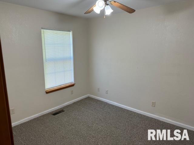 spare room featuring plenty of natural light, a ceiling fan, carpet flooring, and visible vents