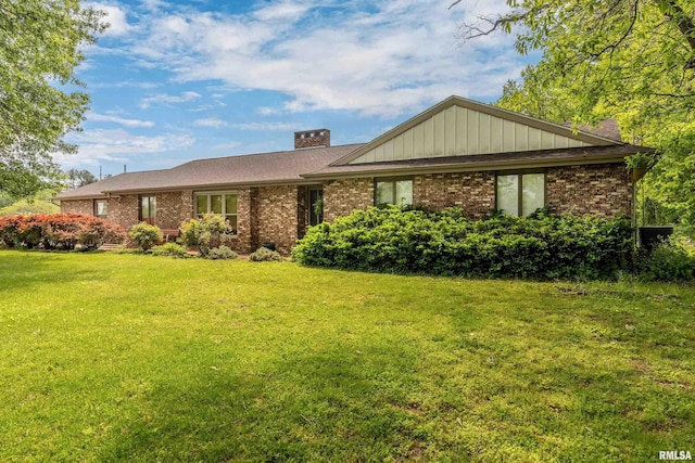 ranch-style home with brick siding, a chimney, and a front lawn