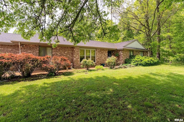 view of front facade featuring brick siding, a shingled roof, and a front lawn