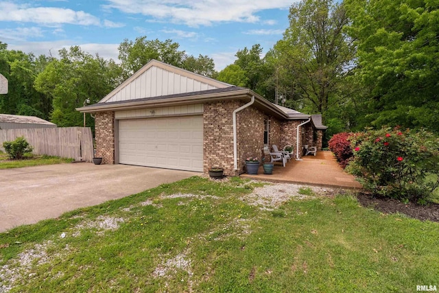 view of side of property with brick siding, an attached garage, fence, and driveway