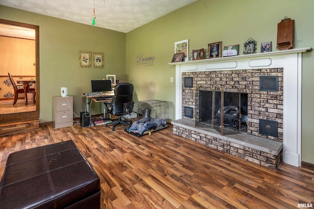 home office with a brick fireplace and wood finished floors