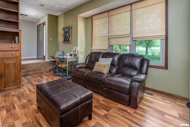 living area featuring baseboards, wood finished floors, and visible vents