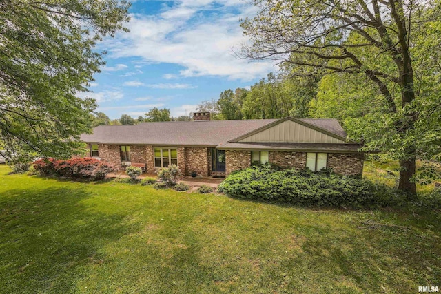 single story home featuring brick siding, a chimney, and a front lawn