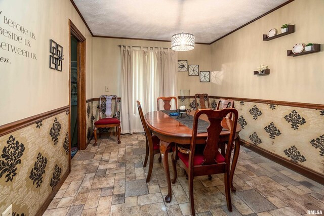 dining space with stone tile flooring, ornamental molding, baseboards, and a textured ceiling