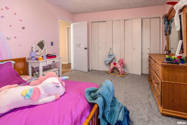 carpeted bedroom featuring a textured ceiling and multiple closets