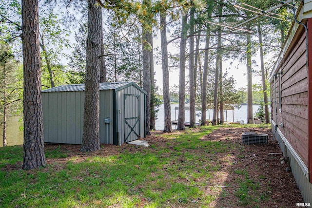 view of yard featuring a storage unit, an outbuilding, a water view, and central AC